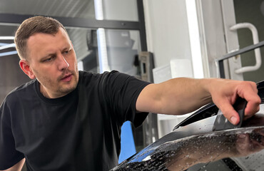 A car wrapping specialist applies a matte polyurethane film to the car. Selective focus. PPF...