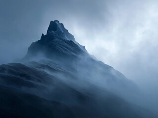 Obraz premium Mist-shrouded mountain peaks pierce the sky, their rugged slopes often dusted with snow, creating a serene winter landscape