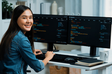 Young Asian in IT developer looking at camera to present with online information on pc with coding...