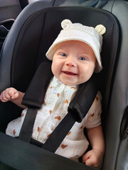 Little newborn baby girl sitting in car seat, child safety and road traffic concept
