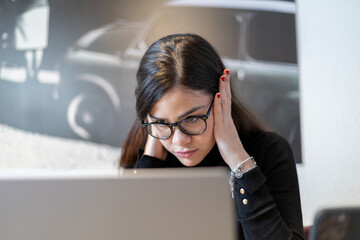Close-up of a stressed woman concentrating on her laptop at home.