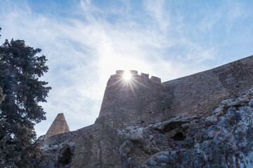 Ancient stone fortress in Lindos, Rhodes, Greece, illuminated by sunlight against a clear blue sky, showcasing Mediterranean architecture and historical significance