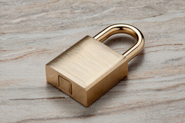 Fototapeta premium Brass padlock sits on smooth marble, emphasizing security and trust in a contemporary setting