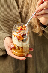 Woman holding and eating layered dessert in a jar