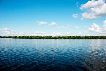 Panoramic view of Dnieper river bank from the embankment of the city of Dnieper. Reflection of the sky with clouds on the surface of the water.