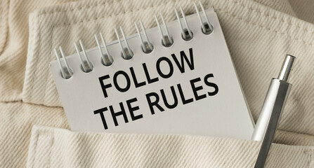 A pen is sitting on a notebook that says Follow the Rules