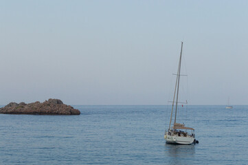 Yachting on a serene seascape at sea. A lone ship sailing on the water on a sunny summer day. Frontal view