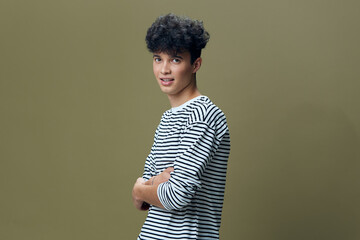 young man in striped shirt posing confidently against olive green background with curly hair and...