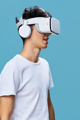 Young man wearing a virtual reality headset and white headphones explores immersive technology...