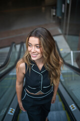 Young woman smiling while going up on escalator