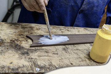 Luthier applying glue to wooden guitar fingerboard