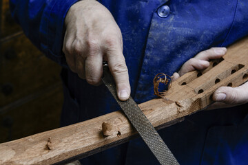 Luthier shaping classical guitar neck with hand file
