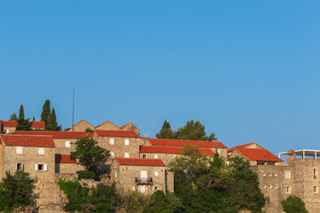 Sveti Stefan Island Hotel, stone houses of a medieval fortress village with tiled roofs on the Adriatic coast of Montenegro