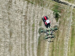 A tractor with a hay tedder in the field, shot with a drone