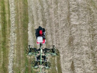 A tractor with a hay tedder in the field, shot with a drone