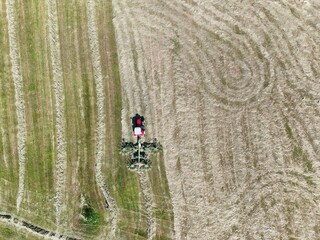 A tractor with a hay tedder in the field, shot with a drone