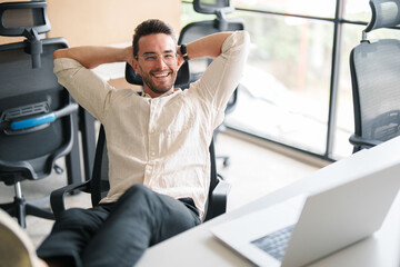 Fototapeta premium Confident Young Man Relaxing in a Bright Modern Office with Minimalist Design and Natural Lighting