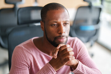 Focused Black Male Professional in a Modern Office Setting Displaying a Thoughtful Expression