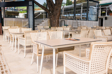 Modern restaurant terrace with set tables and chairs. Casual dining, cozy atmosphere, and summer hospitality experience.