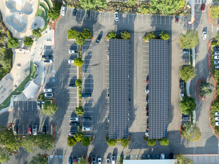 Aerial view of solar panels installed as shade roof over parking lot for parked cars. Photovoltaic technology integrated in urban infrastructure. High quality photo