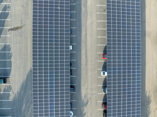 Aerial view of solar panels installed as shade roof over parking lot for parked cars. Photovoltaic technology integrated in urban infrastructure. High quality photo