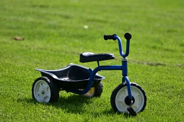 Blue tricycle with trunk. Three wheel bike with trunk on the grass background in countryside. No people