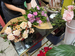 Florist arranging mixed flower bouquets on glass table