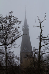 A distant view of a church partially obscured by morning mist, seen from within the peaceful forest...