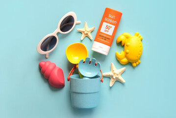 Top view of bottle of sunscreen with 50+ written on it,sunglasses and beach bucket. Concept of sun protection