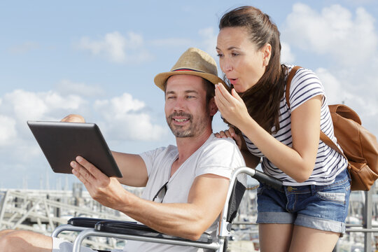 couple amused while looking at tablet man in wheelchair