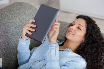 young woman laying in sofa connected with digital tablet
