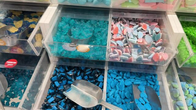 Candy shop display with colorful sweets in transparent bins, including gummy bears and jelly beans