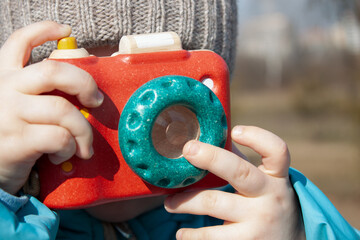 Little photographer with toy camera. Child playing outdoors