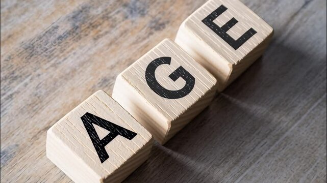 A close-up photo of three wooden cubes with black capital letters spelling the word "AGE," placed on a rustic wooden background.