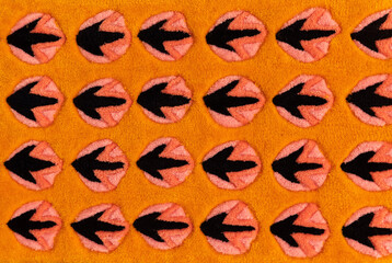 Stylized bird footprints on orange textile carpet