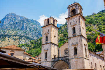 The stunning Cathedral of St. Tryphon, a landmark of Kotor, Montenegro, stands majestically with its twin bell towers against a backdrop of verdant mountains. The bustling square below adds vibrancy © Hope Writing Light