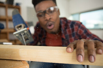 mixed-race carpenter blowing dust from wood