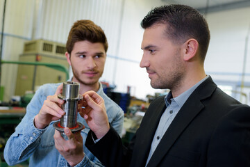 two workers examining metal shaft