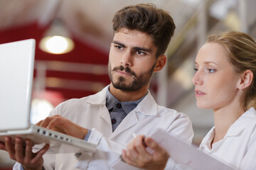 researchers in labcoats are checking laptop