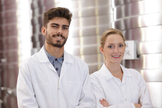 man and woman in lab coats working in a factory