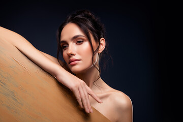 Fototapeta premium Elegant portrait of a young brunette woman with flawless skin posing against a dark background