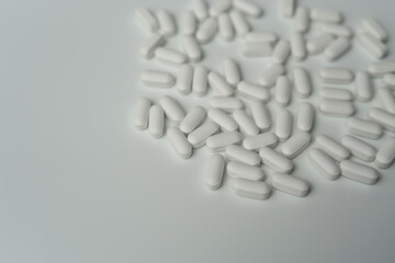 Group of white pills tablets on a light grey background top view