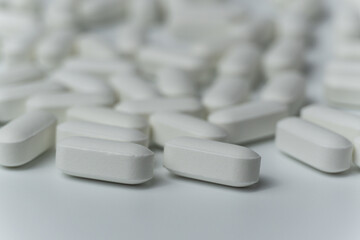 Group of white pills tablets on a light grey background close up macro