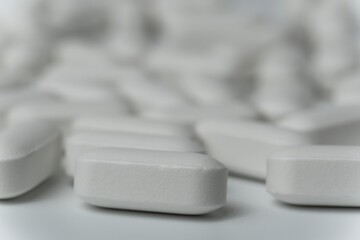 Group of white pills tablets on a light grey background close up macro