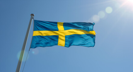 Swedish flag waving against clear blue sky with sun flare. National flag of Sweden blowing in the wind. Sweden National Day celebration concept.