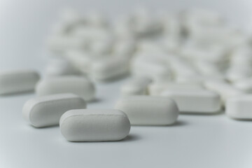 Group of white pills tablets on a light grey background close up macro