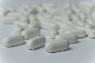 Group of white pills tablets on a light grey background close up macro