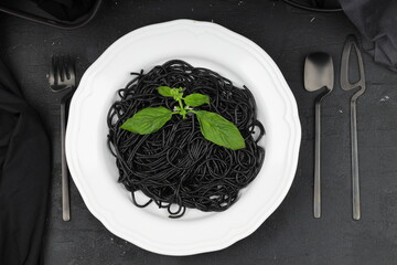 Spaghetti pasta with black ink squids on wooden background.