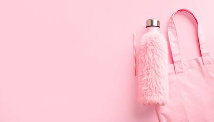 Pink themed reusable bottle, straw, and canvas bag still life on a pink background