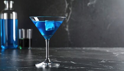 A vibrant blue cocktail in a martini glass, illuminated on a marble countertop